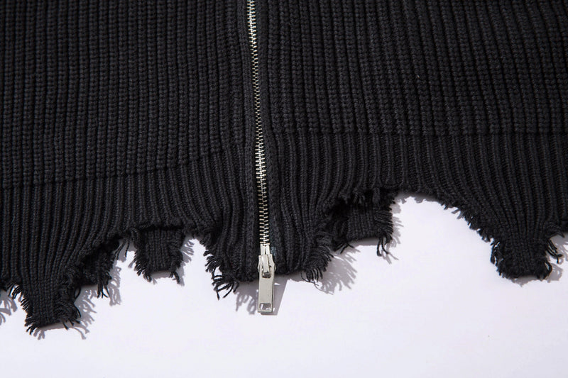 Lower front of black ribbed zip-up cardigan with frayed raw hem and silver zipper