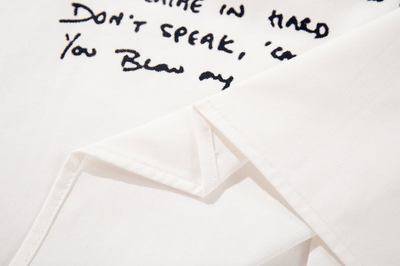 White oversized graphic shirt with handwritten black text and a layered folded hem detail