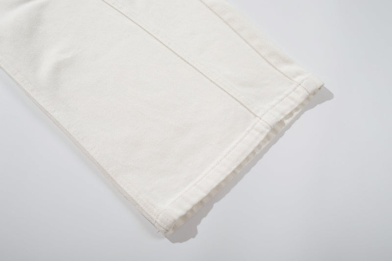 Close-up of the white jean hem showing straight stitching and a wide-leg opening