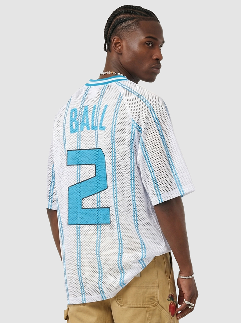Model wearing a white mesh jersey T-shirt with blue stripes and Ball 2 print on the back, styled with tan pants