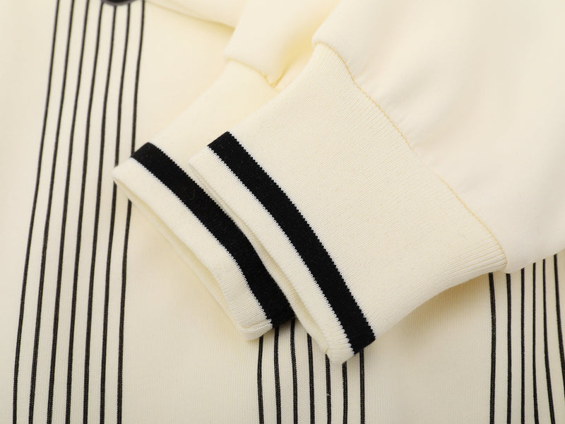Close-up of cream sleeve cuff with black double stripe trim