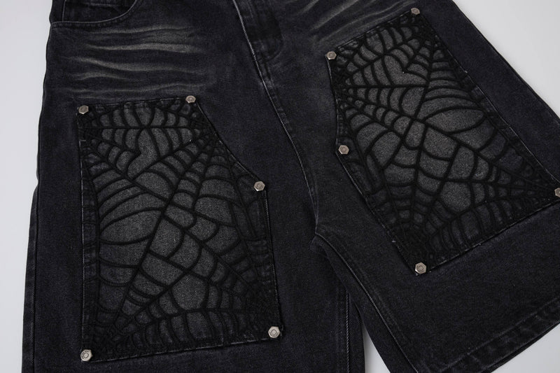 Close-up of black denim shorts back with spiderweb pocket panels and snap buttons