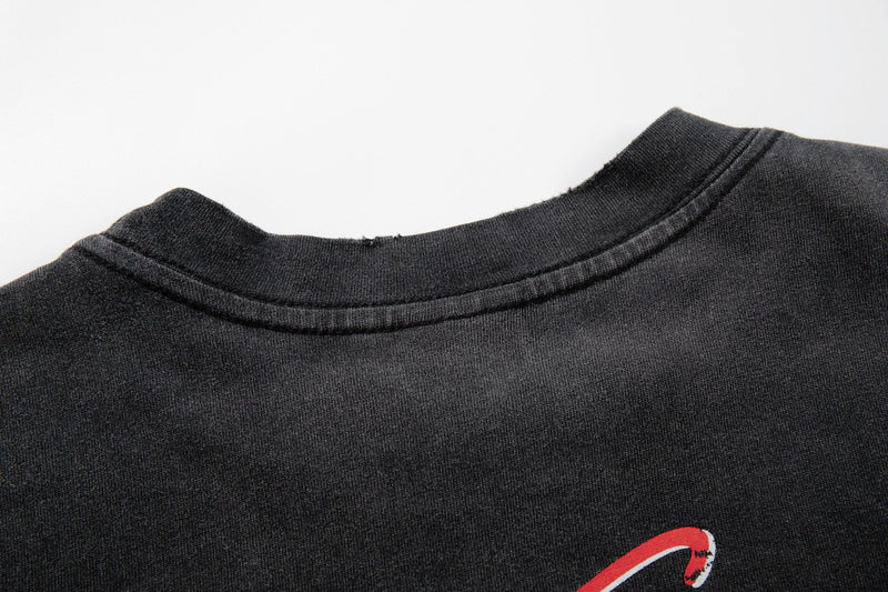Close-up of a black washed graphic tee with ribbed crew neck and red street art print detail