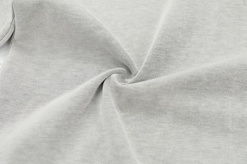 Close-up of light gray ribbed henley tee fabric with contrast stitch detailing and soft relaxed texture
