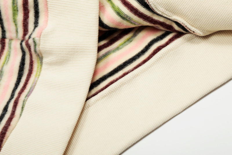 Close-up of striped knit sleeve, pocket edge, and cream hem on hoodie