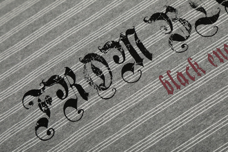 Close-up of Gothic logo print across gray striped long sleeve tee chest
