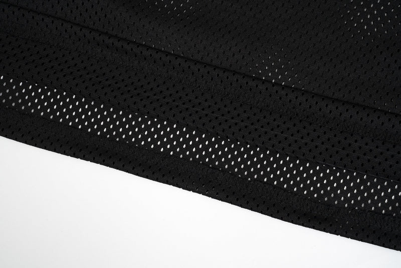Close-up of black mesh fabric and printed hem detail with tiny perforations