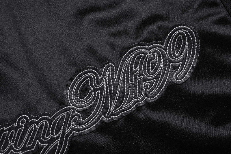 Close-up of embroidered Growing In The World lettering on black jersey
