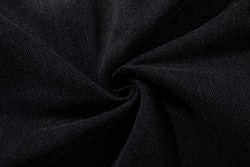 Close-up of black denim fabric texture with soft folds and diagonal weave