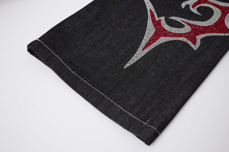 Close-up of black denim hem with partial rhinestone flame design