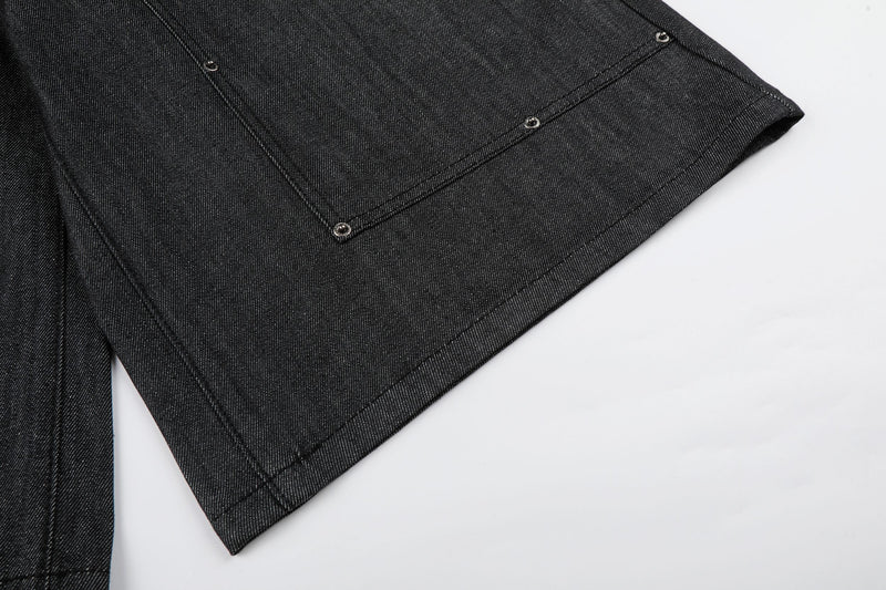 Close-up of hem on black wide-leg denim shorts showing stitched edge and rivet detail