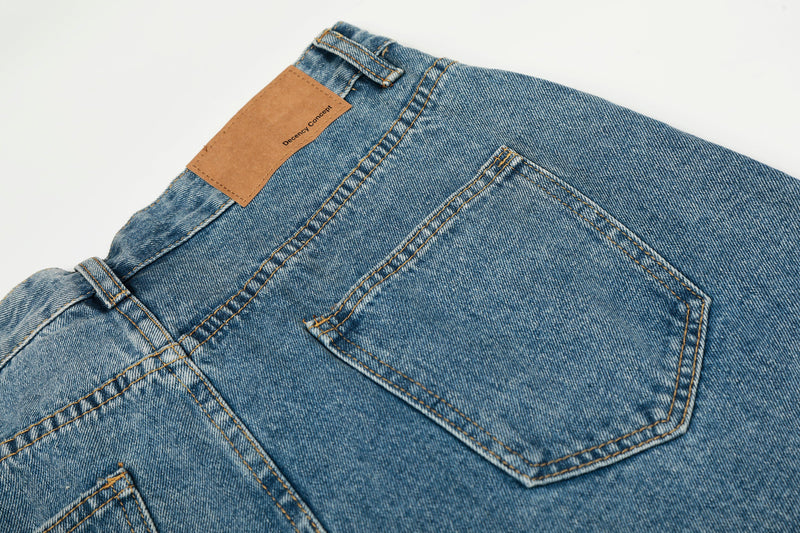 Back view close-up of blue denim jeans with tan label and left pocket