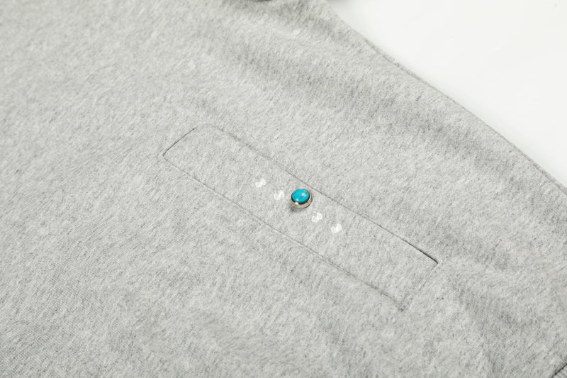 Close-up of light gray hoodie pocket with turquoise dot detail