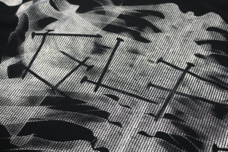 Close-up of black-and-white oversized tee fabric with a bold skeleton-style graphic print and textured mesh-like pattern