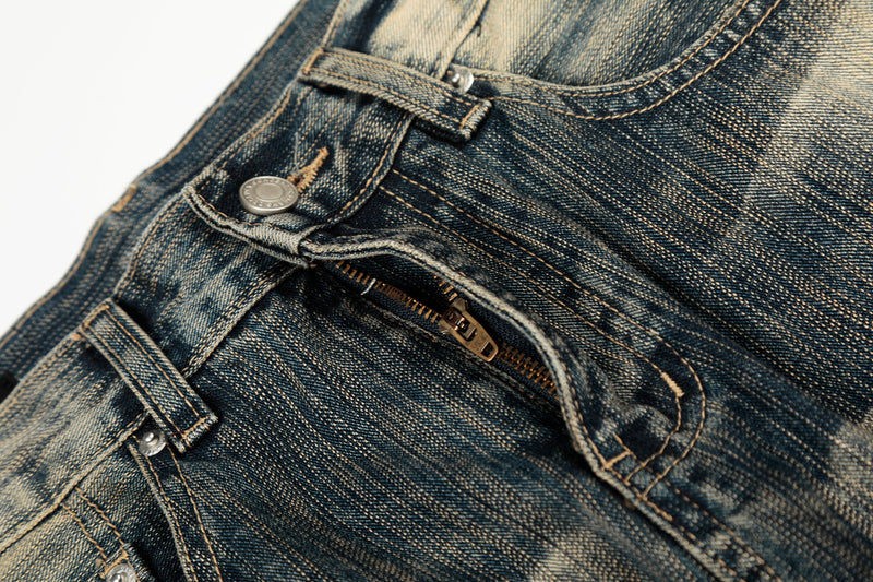Close-up of the front fly with zipper and button on washed denim pants