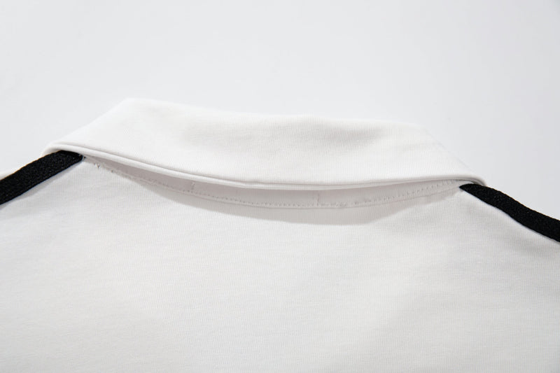 White racing crest polo shirt with black shoulder trim and a clean folded collar on a minimalist background