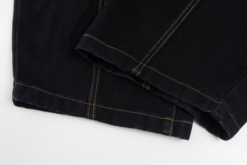 Folded black denim hem with tan topstitching and wide-leg opening