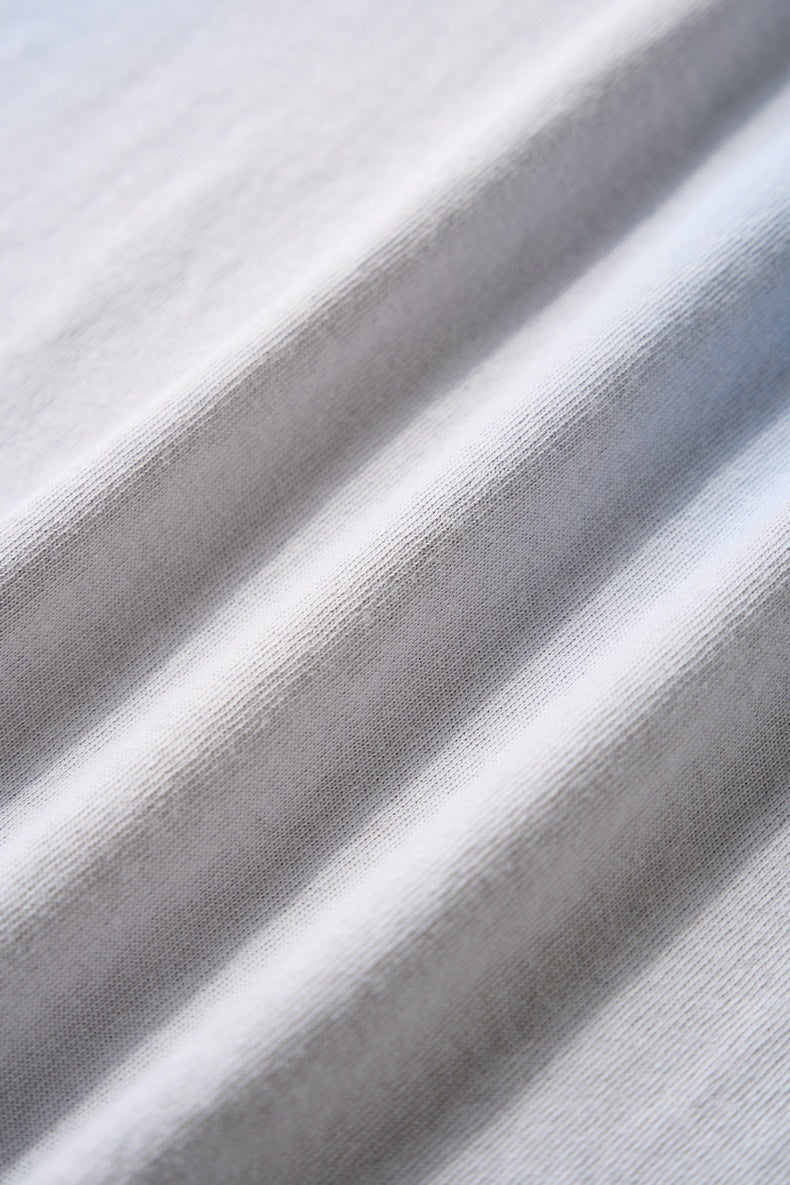 Close-up of soft white vintage spray-dyed tee fabric with subtle ribbed texture and draped folds
