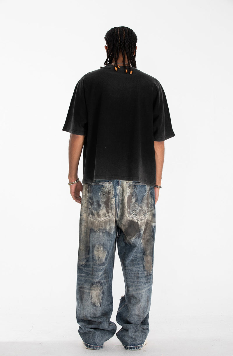 Black oversized gothic graphic tee styled with loose faded jeans on a model photographed from the back