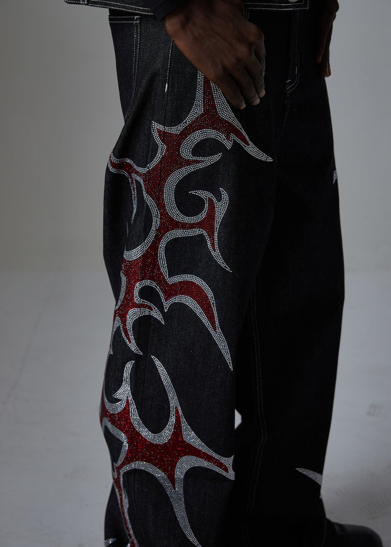 Close-up side view of black denim pants showing a red flame rhinestone design