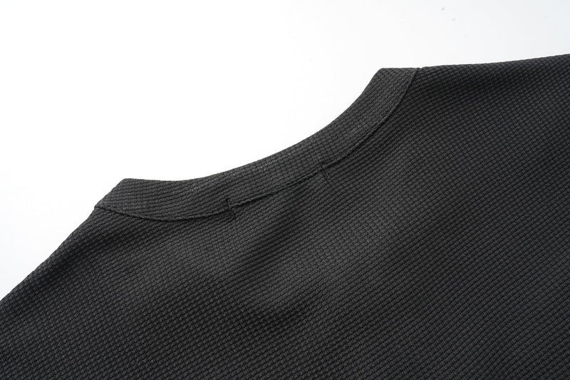 Close-up of black waffle-knit sleeve and shoulder seam on long sleeve tee