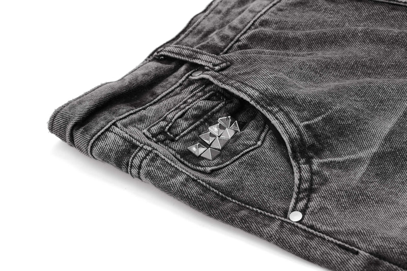 Close-up of front pocket with silver pyramid studs on distressed denim