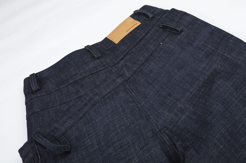 Angled back waist detail of dark denim jeans with tan label patch