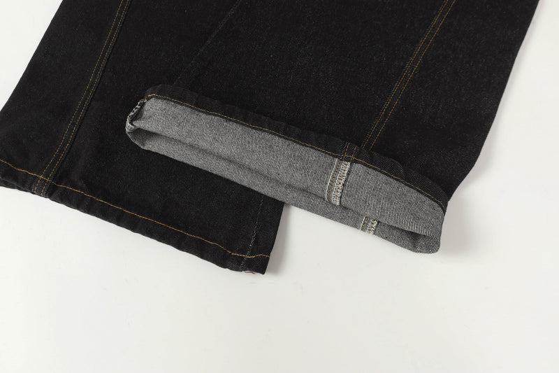 Close-up of the hem on black denim pants showing folded cuff and light inner fabric