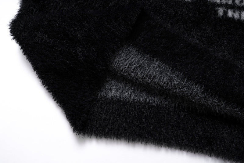 Close-up of the black fuzzy sweater hem with layered plush knit texture