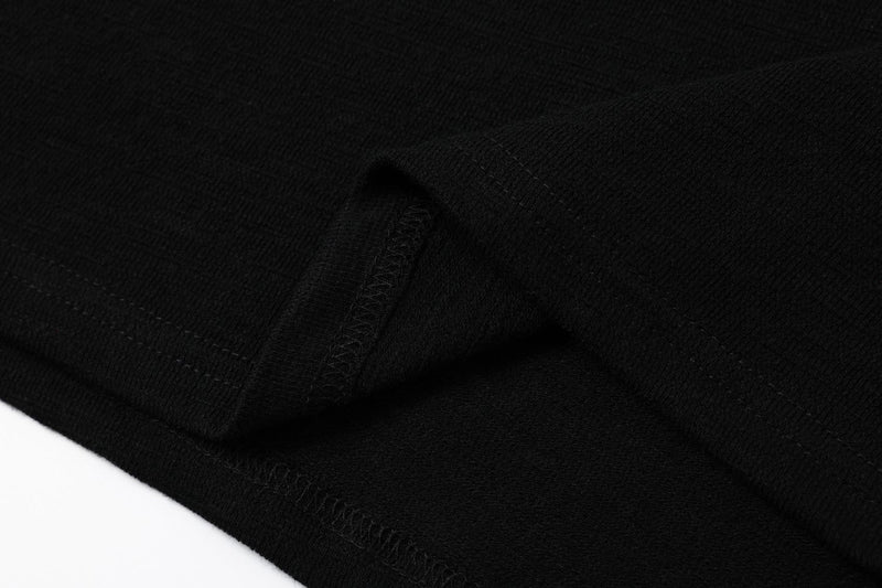 Black textured polo shirt fabric with subtle stripe detail and ribbed stitching, shown in a close-up streetwear style shot