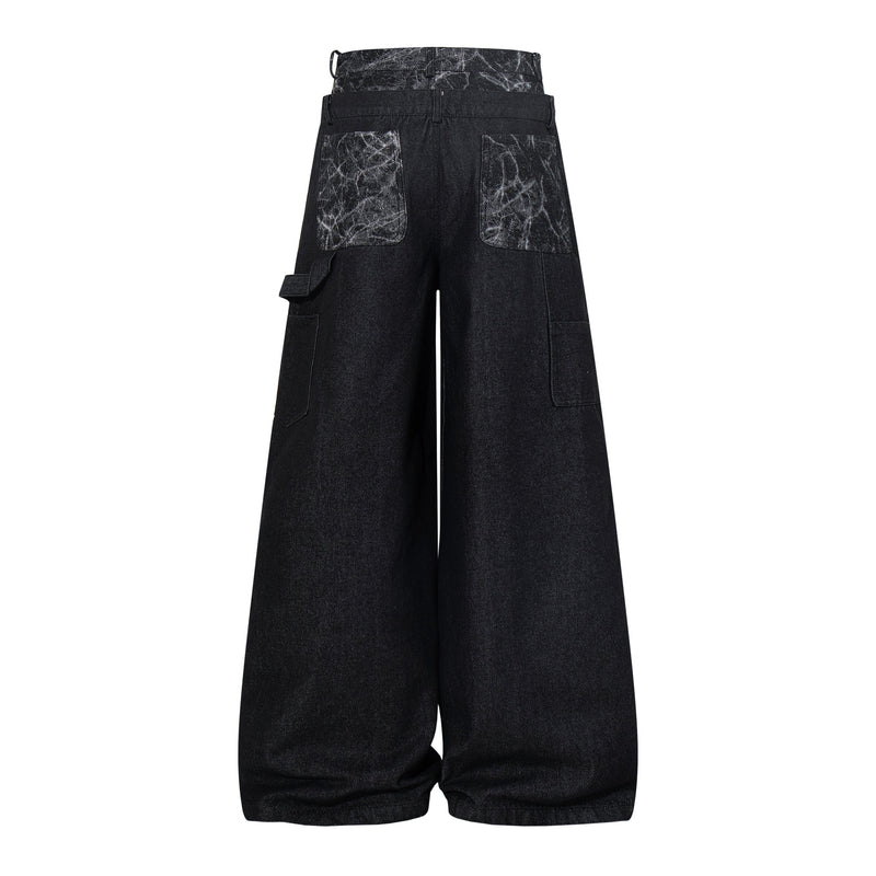 Back view of black wide-leg denim pants with cracked panel pockets and side strap detail