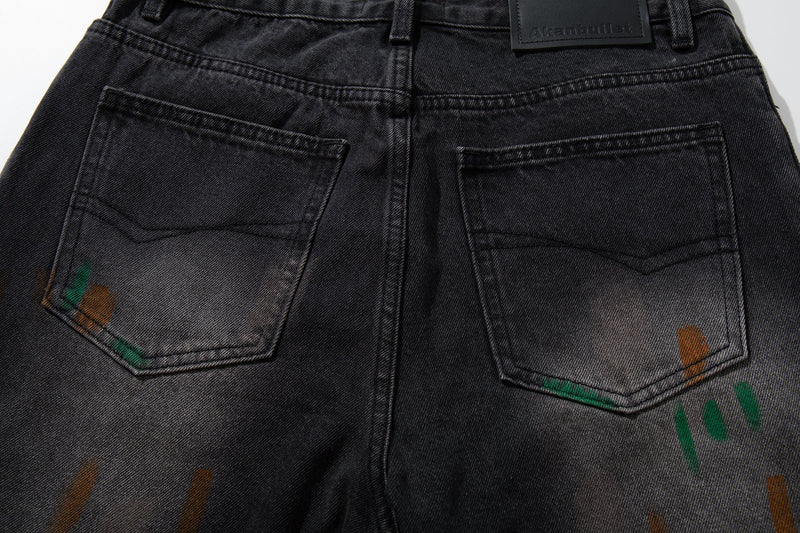 Close-up of back pockets on washed black jeans with faded painted streaks