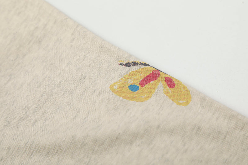 Close-up of yellow butterfly print on cream tee sleeve