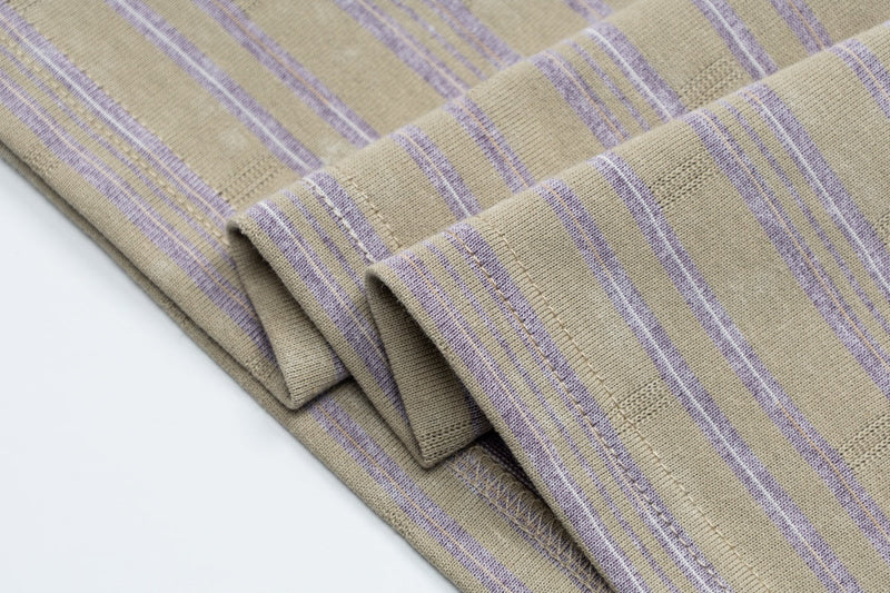 Close-up of folded beige striped ringer T-shirt with lavender accents and ribbed knit fabric detail