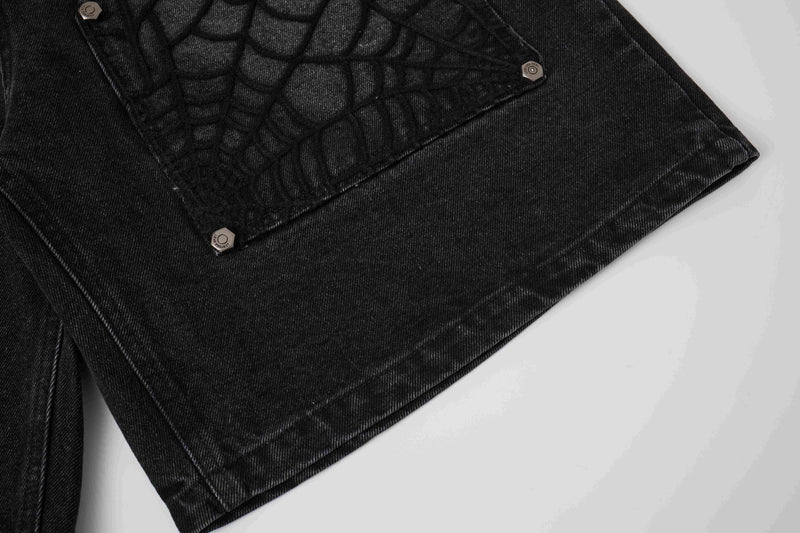 Close-up of black denim shorts spiderweb panel with snap buttons and denim texture