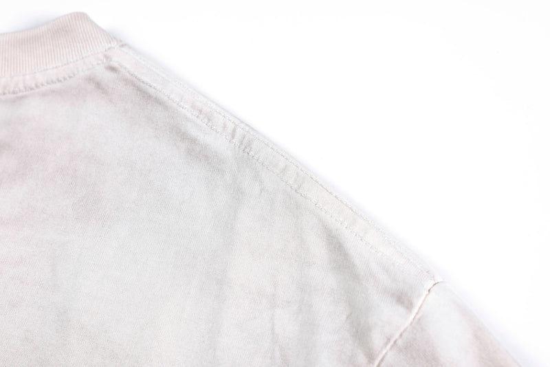 Close-up of a faded white vintage washed tee shoulder seam with soft Y2K streetwear style
