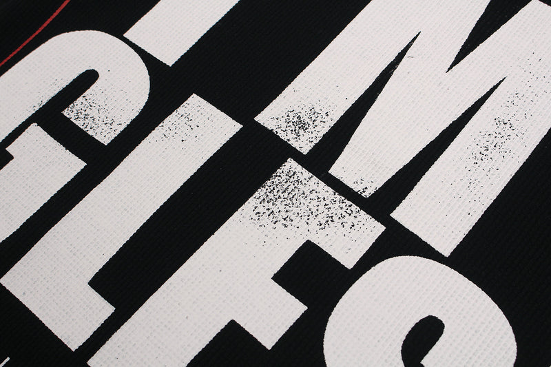 Close-up of a black graphic T-shirt with bold white newspaper-style lettering and distressed print details