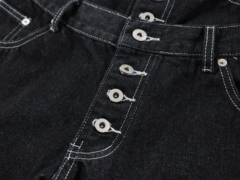 Close-up of the front button placket and seam stitching on black denim pants