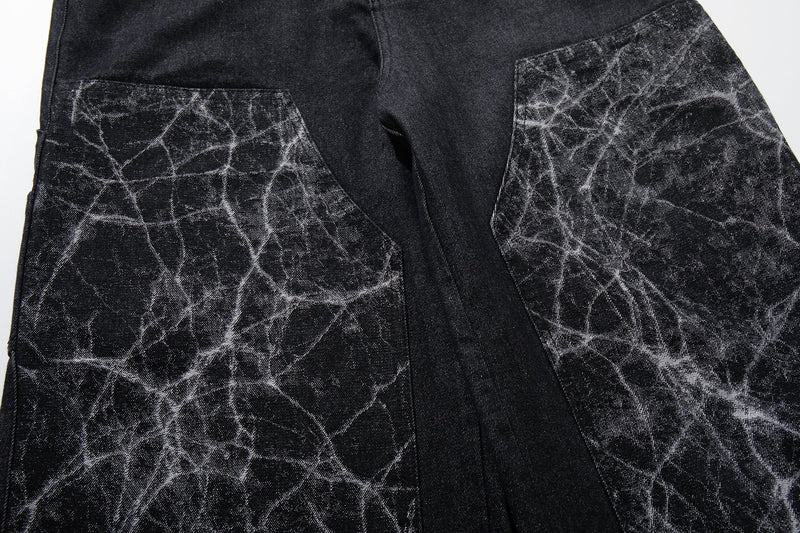Close-up of back waistband and cracked panel patch pockets on black wide-leg denim pants