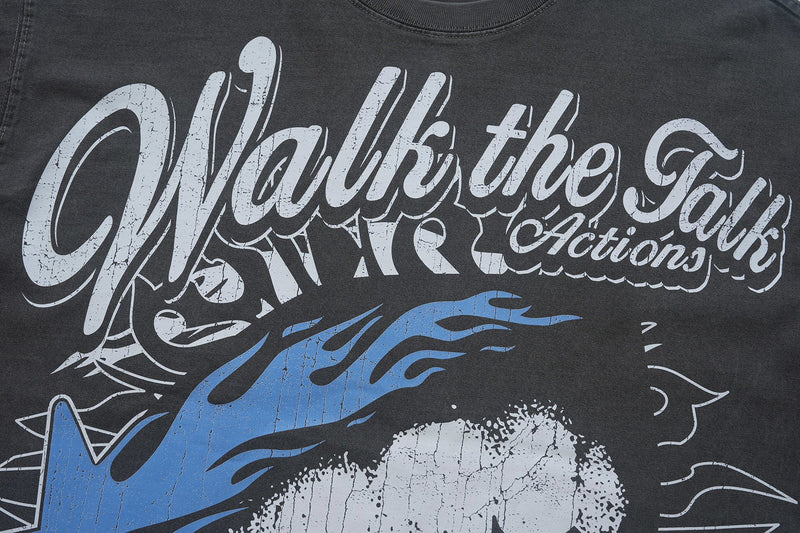 Black vintage-washed graphic T-shirt with oversized distressed Walk the Talk text and blue retro artwork on the front