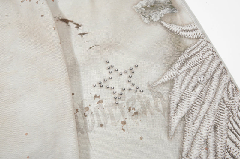 Close-up of back leg with studded star motif and wing print on cream denim