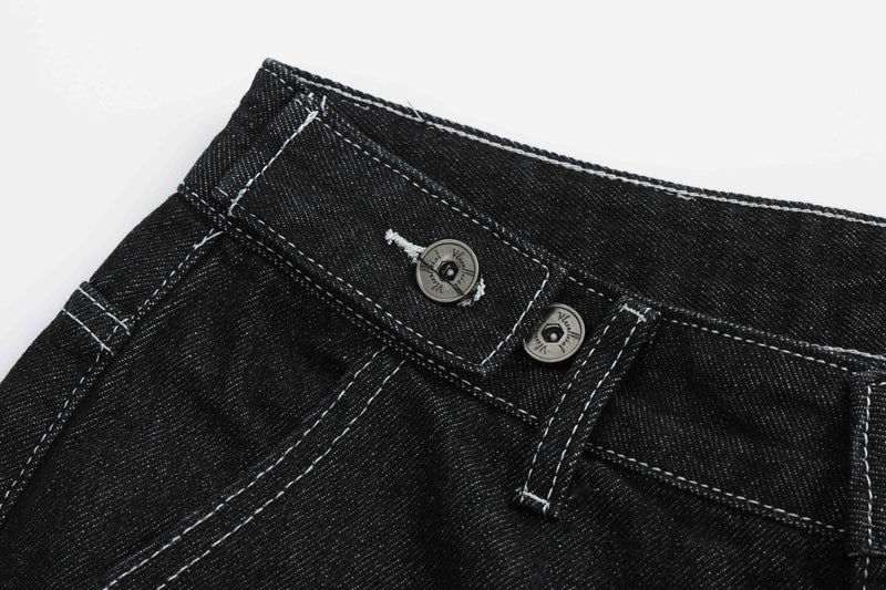 Top corner close-up of black denim shorts with waistband buttons and stitched seams