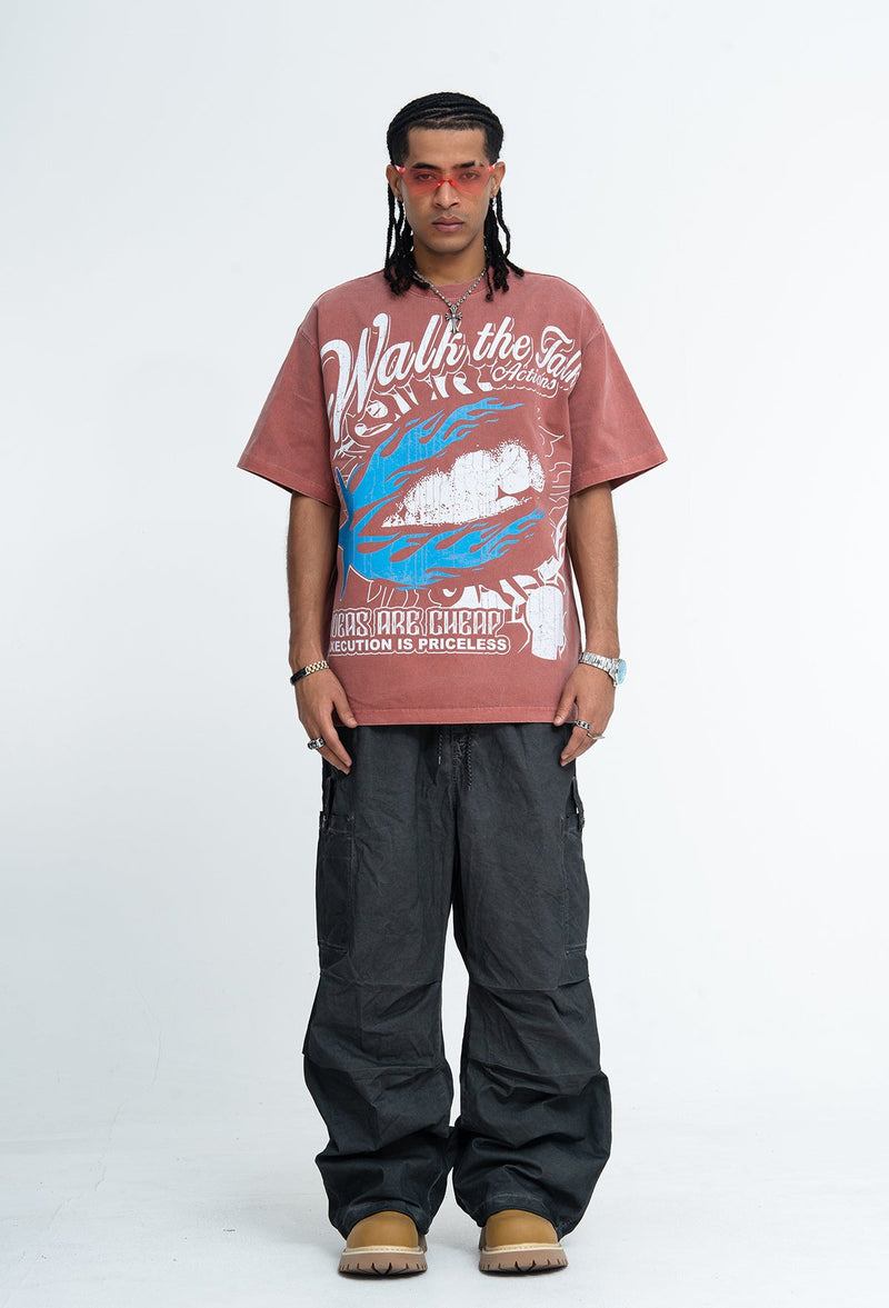 Vintage washed rust graphic T-shirt with bold walk-the-talk print, worn with black cargo pants and tan boots on model