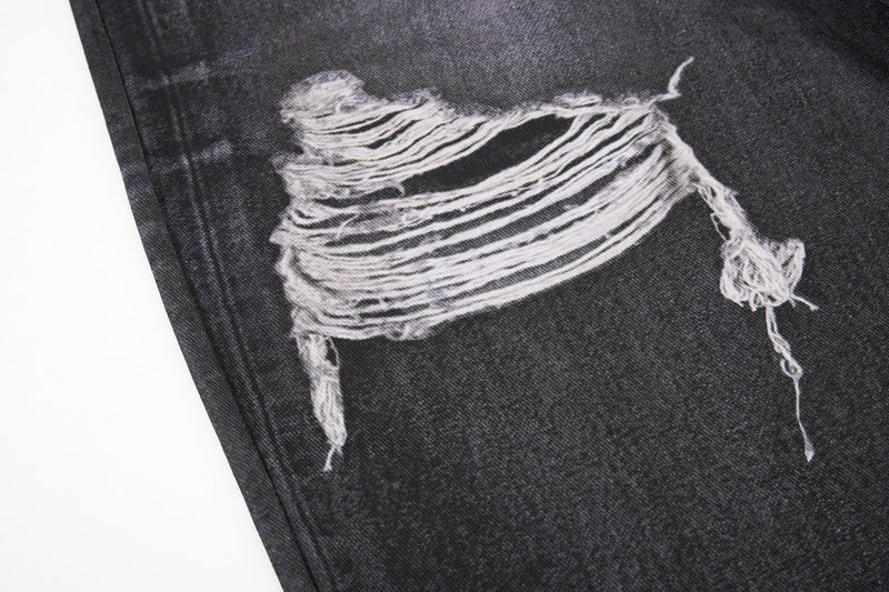 Close-up of torn black denim knee with exposed frayed white threads