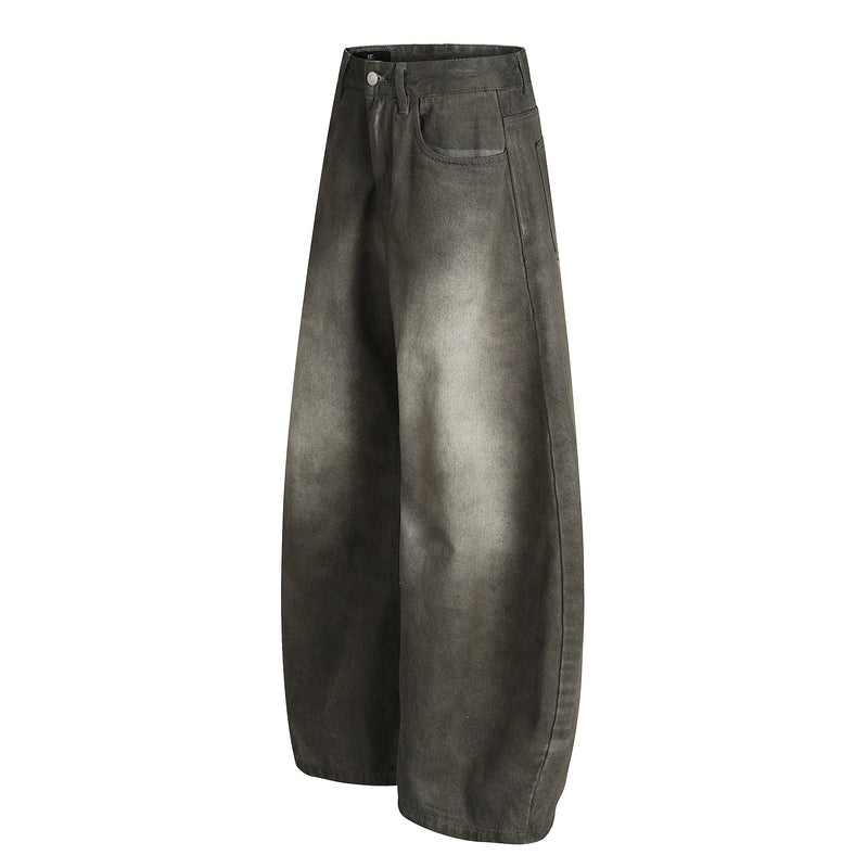 Side view of faded black wide-leg denim pants with curved leg shape and vintage wash