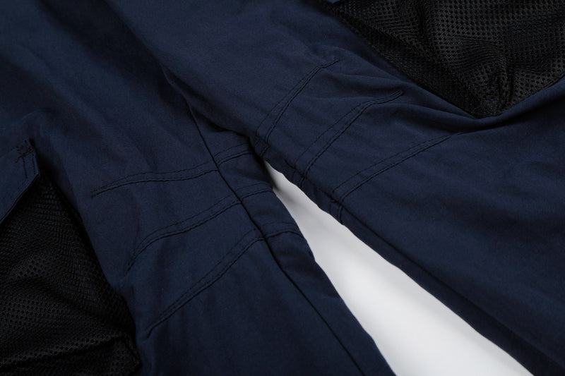 Close-up of navy cargo pants knee area with seam lines and mesh pocket edge