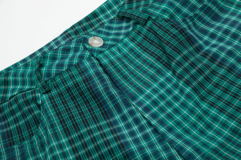 Close-up of green plaid shorts front pocket and button detail