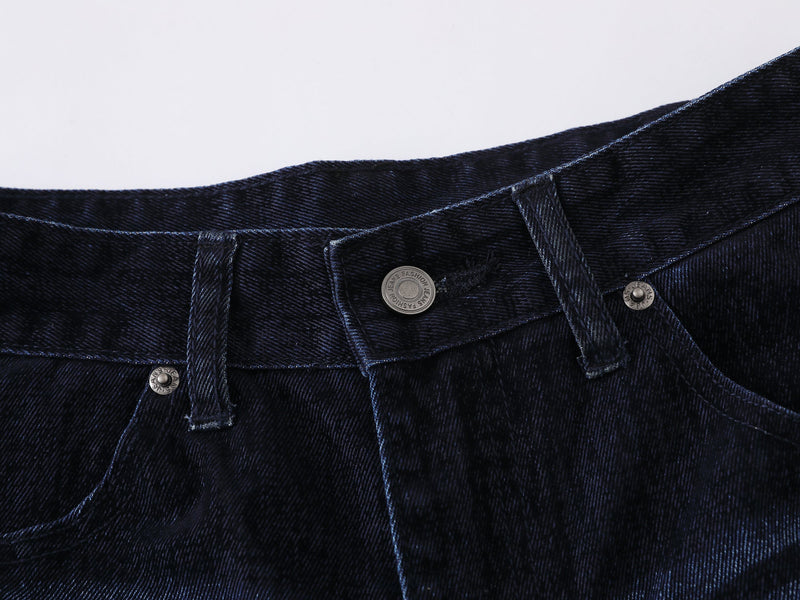 Close-up of the denim waistband with button, belt loops, and faded indigo texture