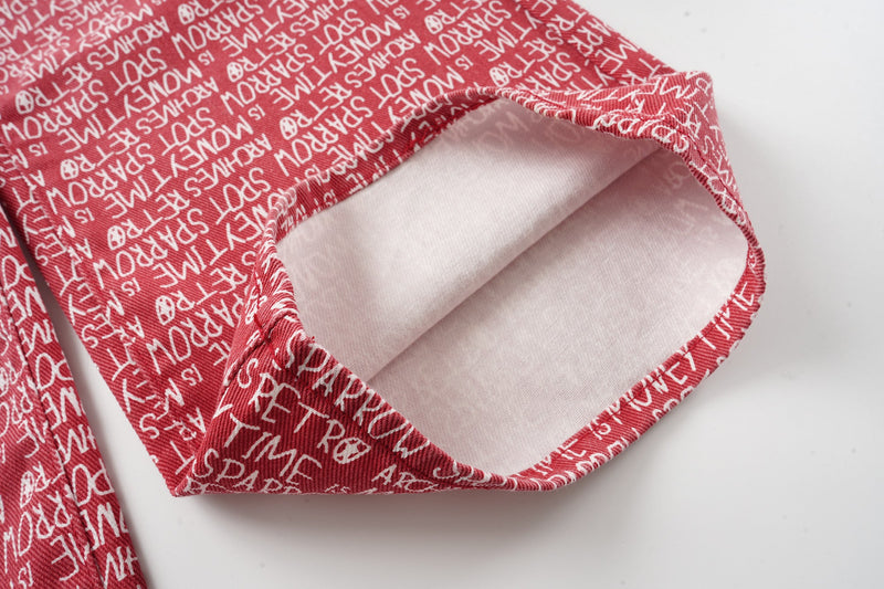 Close-up of red pants leg hem with white script print and folded cuff