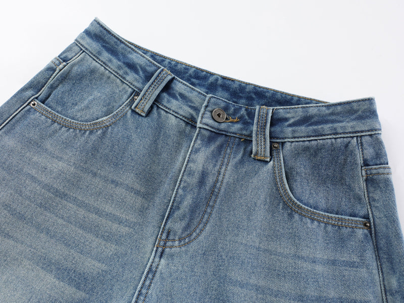 Close-up of the front waistband, button, and pocket on light blue denim pants